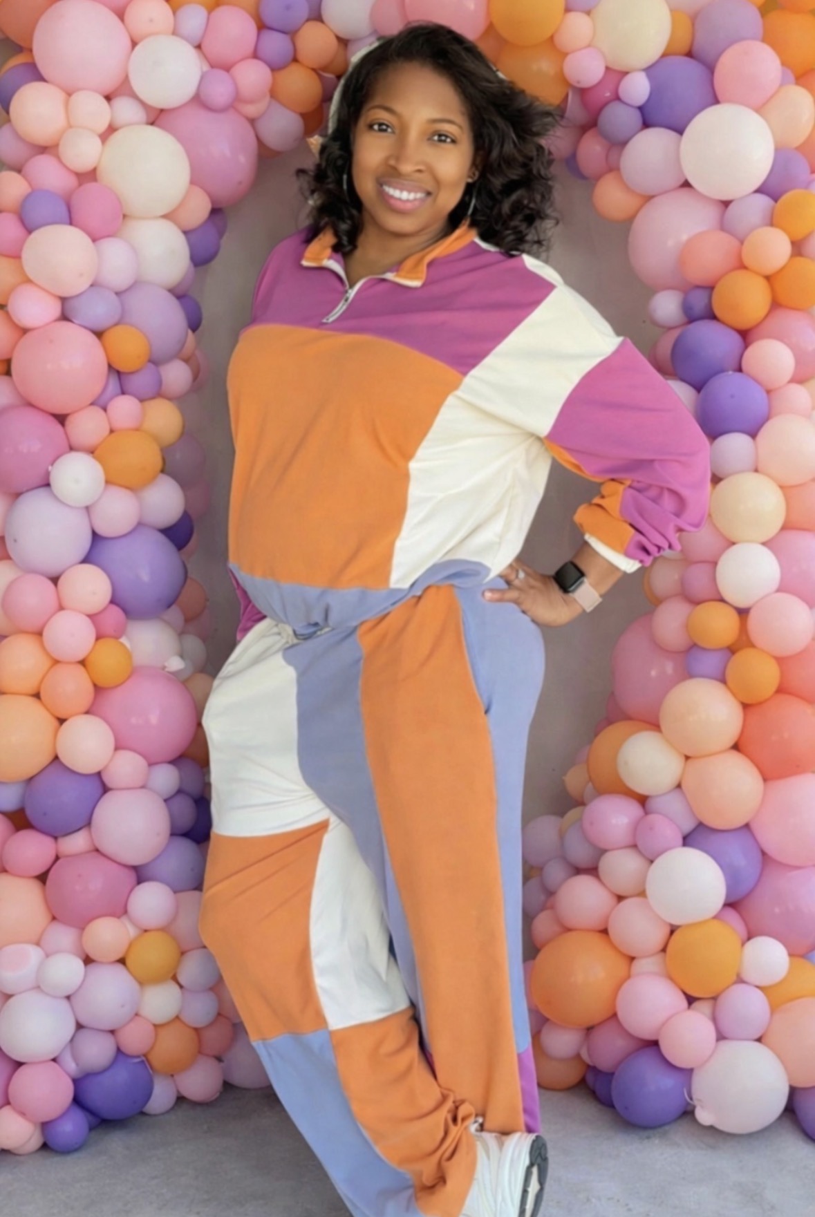 Owner and creative designer of DTD Creations standing in front of a colorful balloon arrangement